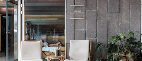 L’entrée d’un sauna finlandais, avec des fauteuils en osier et une plante en pot.