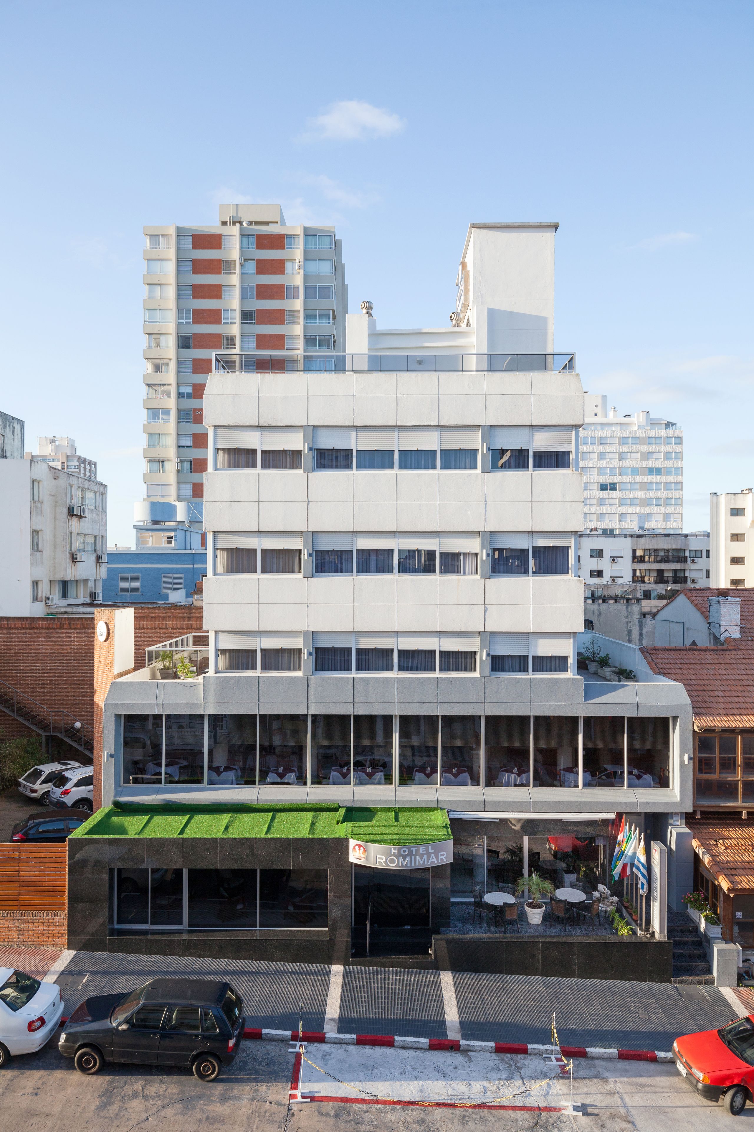 Un hotel de diseño moderno, con techo plano, grandes ventanales y un toldo verde.