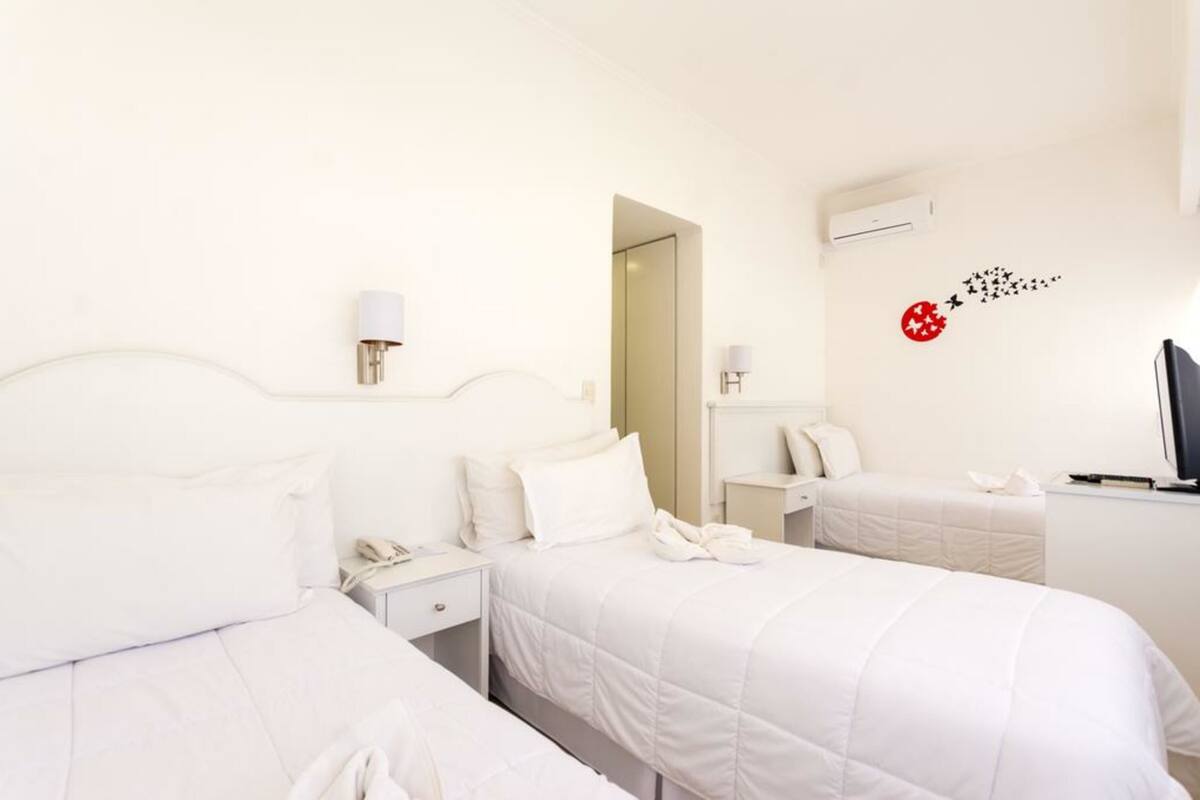 A hotel room with two beds, a TV, a desk, and a mirror.