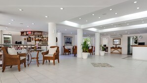 Un hall d’entrée spacieux, doté de meubles en osier, d’un bar et d’une grande fenêtre.