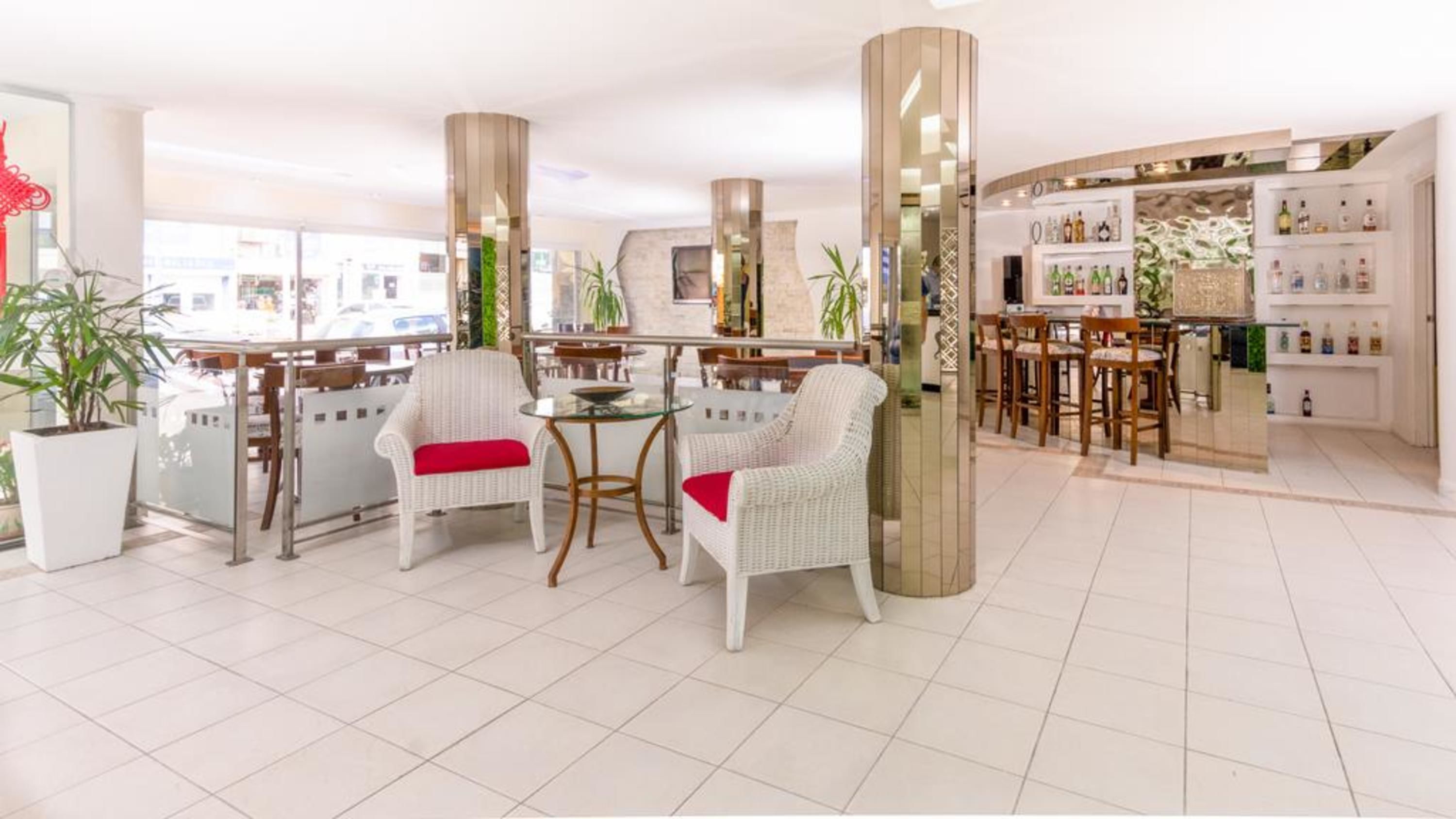 A modern bar area with wicker chairs, a round table, and a bar counter.