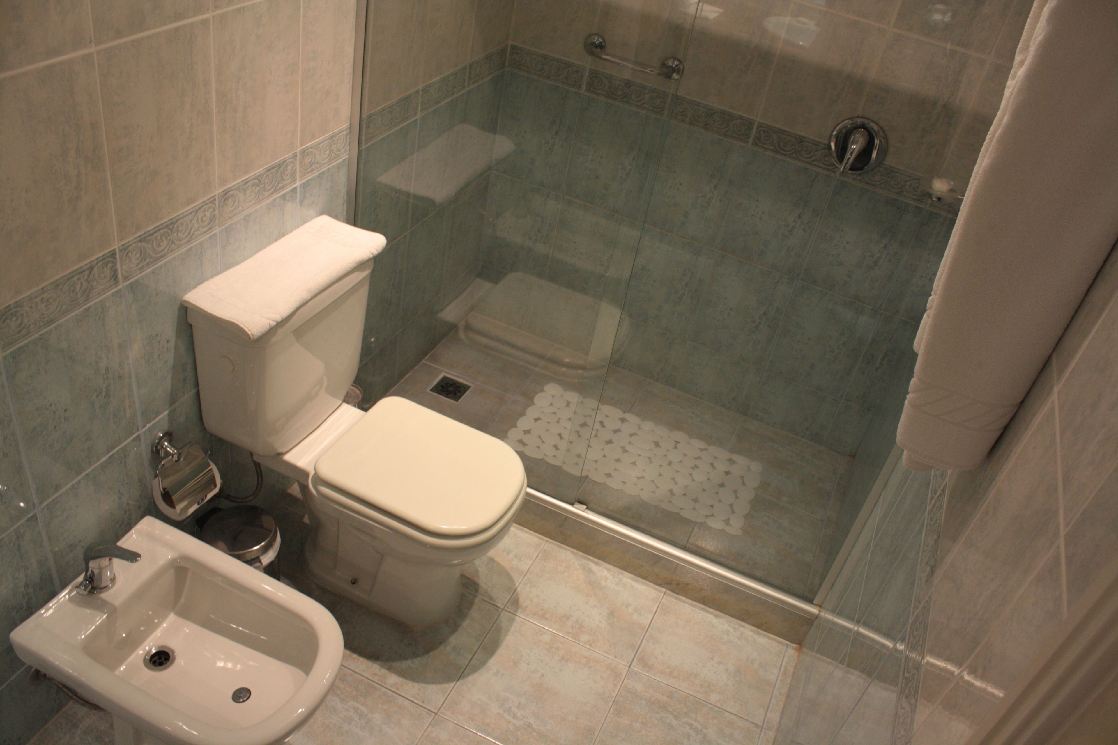 Une salle de bain équipée de toilettes, d’un bidet et d’une douche à parois de verre.
