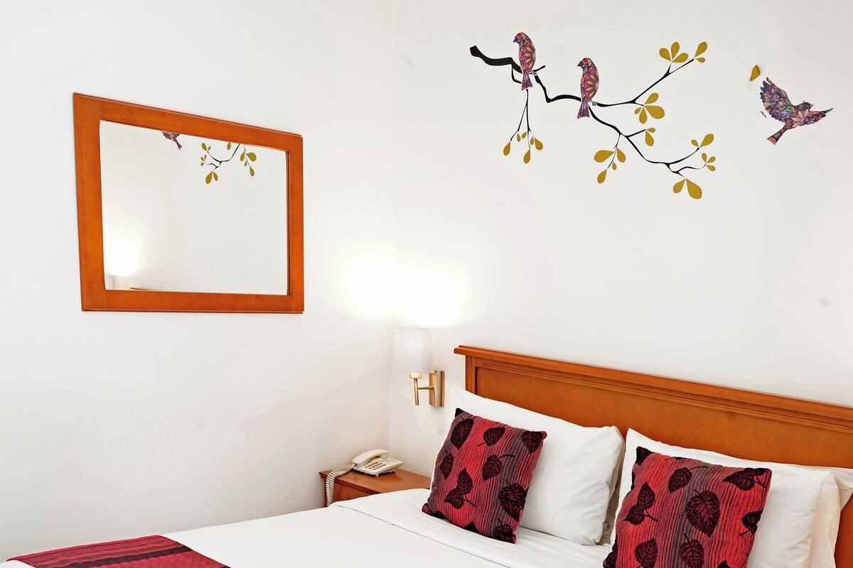 A neatly made bed with a red and white striped blanket, a wooden headboard, and two matching pillows.