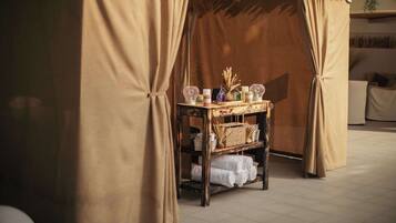 A room with a canopy bed, a small table with toiletries, and a basket of towels.