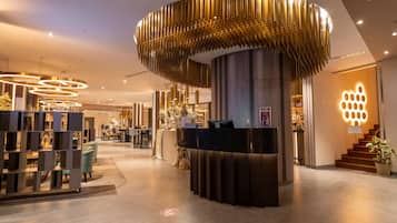 A hotel reception area with a modern design, including a circular light fixture and a reception desk.