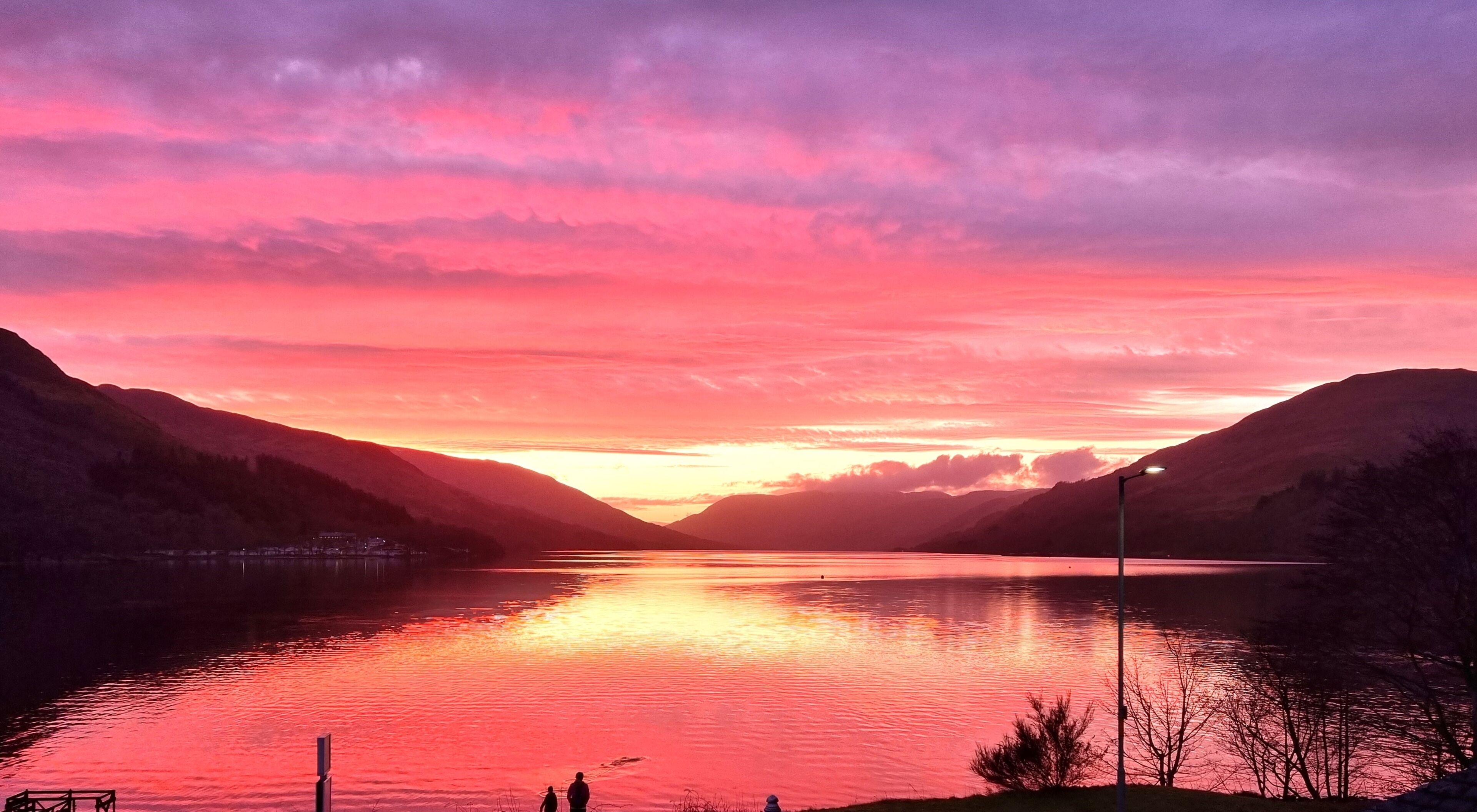 Atardecer sobre un lago flanqueado por montañas.