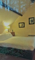 Un dormitorio con una cama, una mesita de noche, una lámpara y cuadros en la pared.
