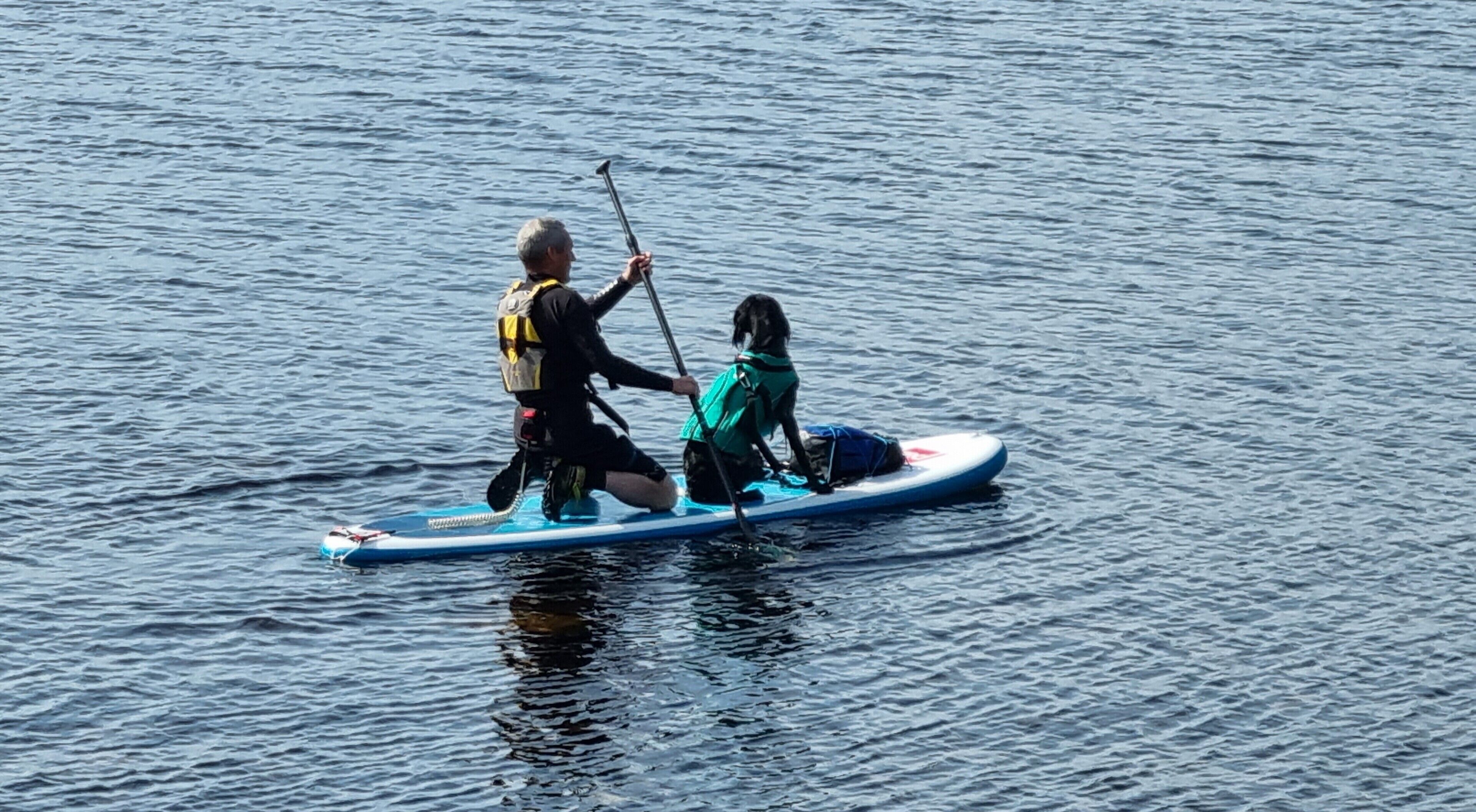 Two people on a paddleboard in calm water.
