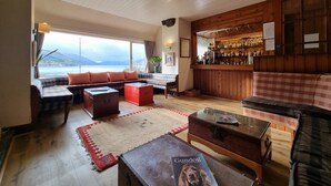Una sala de estar acogedora con un ventanal grande con vistas panorámicas, una barra con fondo de madera y cómodos asientos.