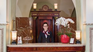 A reception desk with a nameplate, a clock, and two lamps. - Grand Hotel (Kraków)