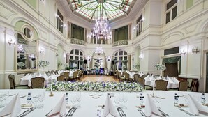 A grand ballroom with ornate chandeliers, white floral arrangements, and formal dining tables set for a large event. - Grand Hotel (Kraków)