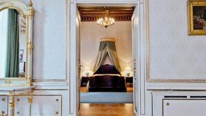A luxurious bedroom with a large bed, ornate furniture, and a chandelier. - Grand Hotel (Kraków)
