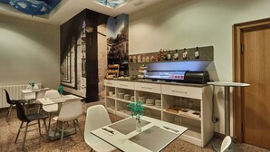 A hotel room with a dining area, a buffet with various food items, and a coffee station. - Silken Sirimiri (Bilbao)