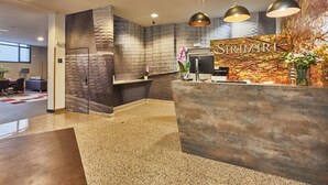 A reception area with a stone wall, a reception desk, and a large window. - Silken Sirimiri (Bilbao)