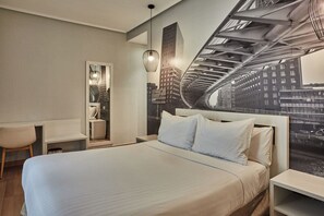 A modern hotel room with a bed, a desk, a chair, and a cityscape mural on the wall. - Silken Sirimiri (Bilbao)
