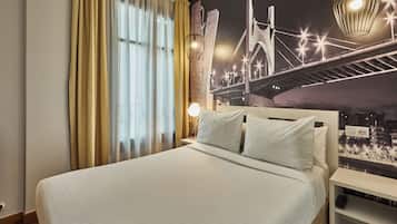 Habitació d'hotel amb un llit gran, un mural de paisatge urbà, una taula de nit i una làmpada.
