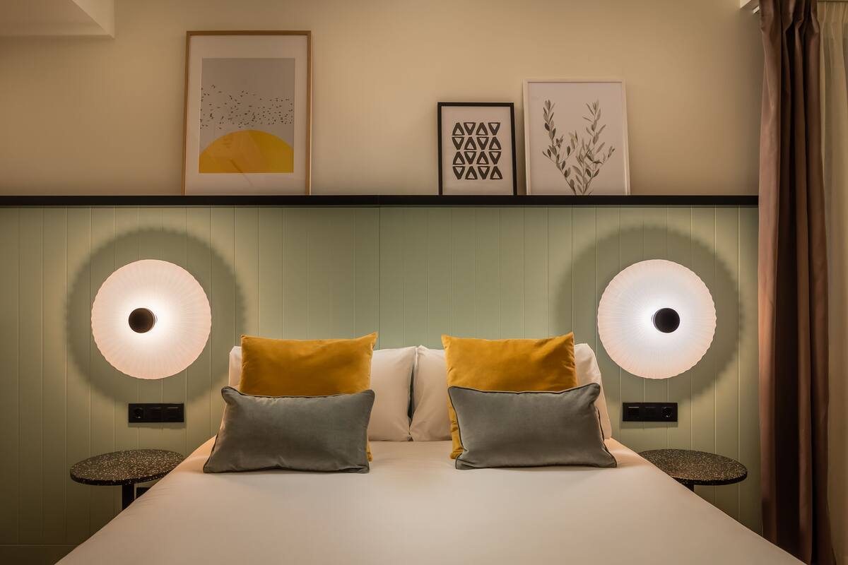 A bedroom with a bed, two bedside tables, and wall-mounted lamps.