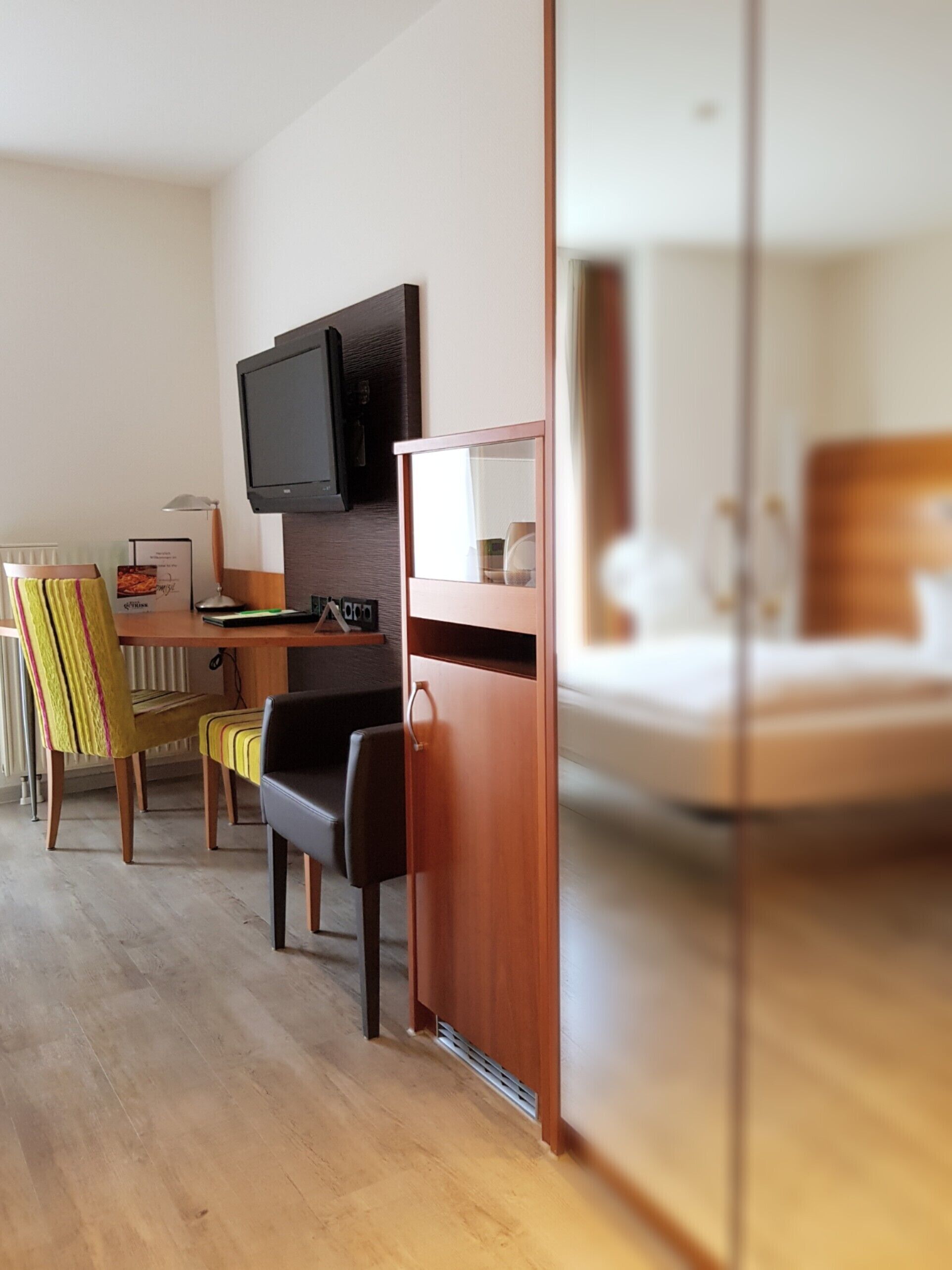 Ein Hotelzimmer mit einem Holztisch, einem Fernseher, einem Bett und einem Stuhl.