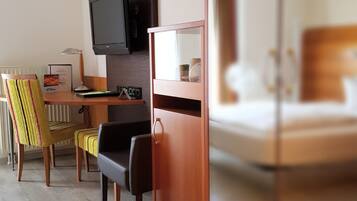 Ein Hotelzimmer mit einem Holztisch, einem Fernseher, einem Bett und einem Stuhl.