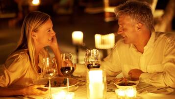 A couple dining at a table with candles, wine glasses, and a lit candle centerpiece.