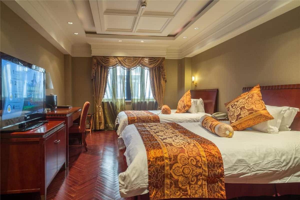 A hotel room with a large bed, a desk with a computer, and a TV.
