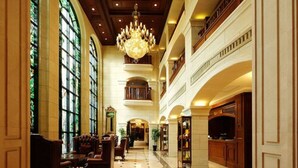 Un vestíbulo imponente con techos altos, grandes candelabros y una escalera central.