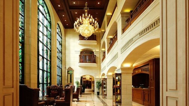 Un vestíbulo imponente con techos altos, grandes candelabros y una escalera central.