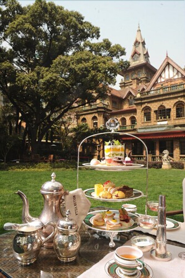 A tea service set on a table with a view of a large building in the background. - Moller Villa Hotel Shanghai (Shanghai)