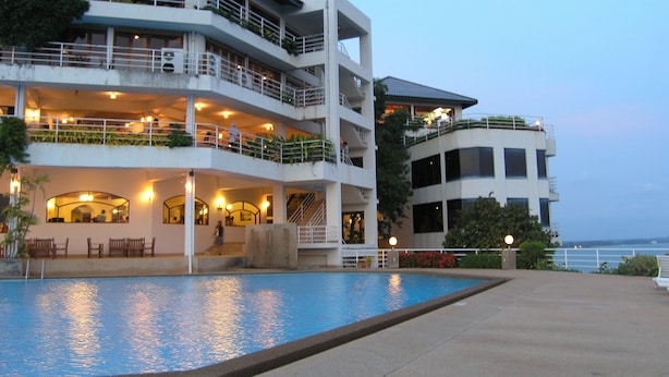 Ein mehrstöckiges Hotel mit Swimmingpool, Balkonen und Sitzbereichen im Freien.