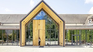 Un bâtiment moderne doté d’une façade triangulaire en bois et de grandes fenêtres en verre.