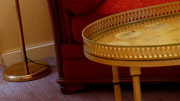 A red sofa with patterned cushions, a round glass coffee table, and a floor lamp.