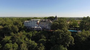 A large, multi-story building surrounded by dense trees, likely a hotel or resort.