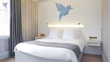 Une chambre d’hôtel moderne, dotée d’un grand lit, d’une table de chevet, d’une lampe fixée au mur et d’un élément décoratif mural.