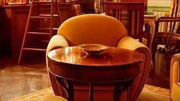 Una habitació acollidora amb una taula rodona, una cadira, una escala i una biblioteca plena de llibres i objectes decoratius.