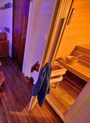 A sauna room with wooden benches, a towel rack, and a wooden door.