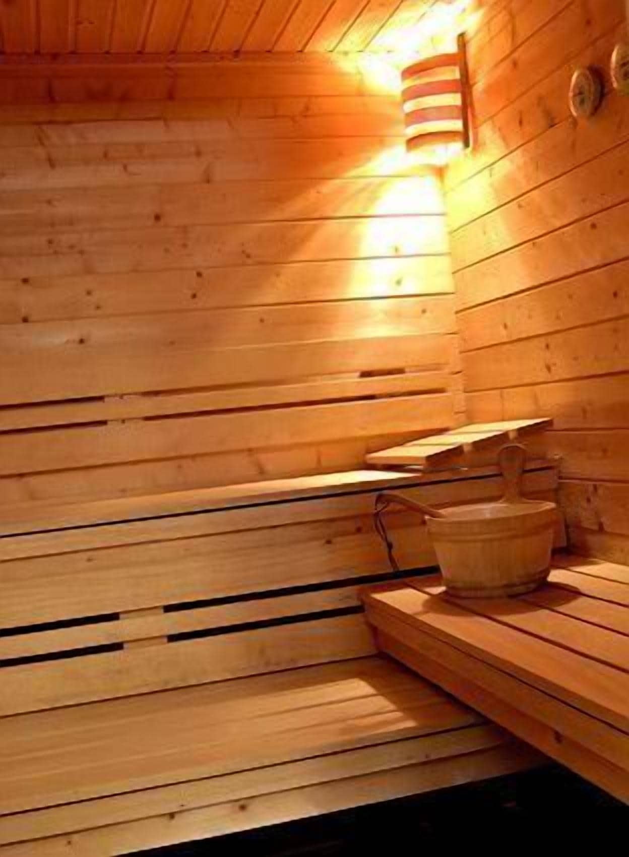 A wooden sauna with benches and a bucket.