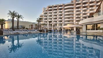 Una piscina cubierta, una piscina al aire libre, sombrillas