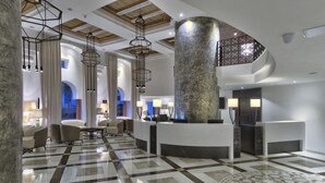 A modern lobby with a checkered floor, a reception desk, and a staircase. - db San Antonio Hotel & Spa - All Inclusive (St. Paul's Bay)