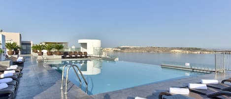 Una piscina cubierta, una piscina al aire libre, sombrillas