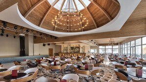 A spacious indoor area with a high ceiling and a central chandelier, surrounded by numerous tables and chairs. - db San Antonio Hotel & Spa - All Inclusive (St. Paul's Bay)
