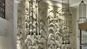 A lobby with a textured wall, modern chairs, a floor lamp, and hanging light fixtures. - db San Antonio Hotel & Spa - All Inclusive (St. Paul's Bay)