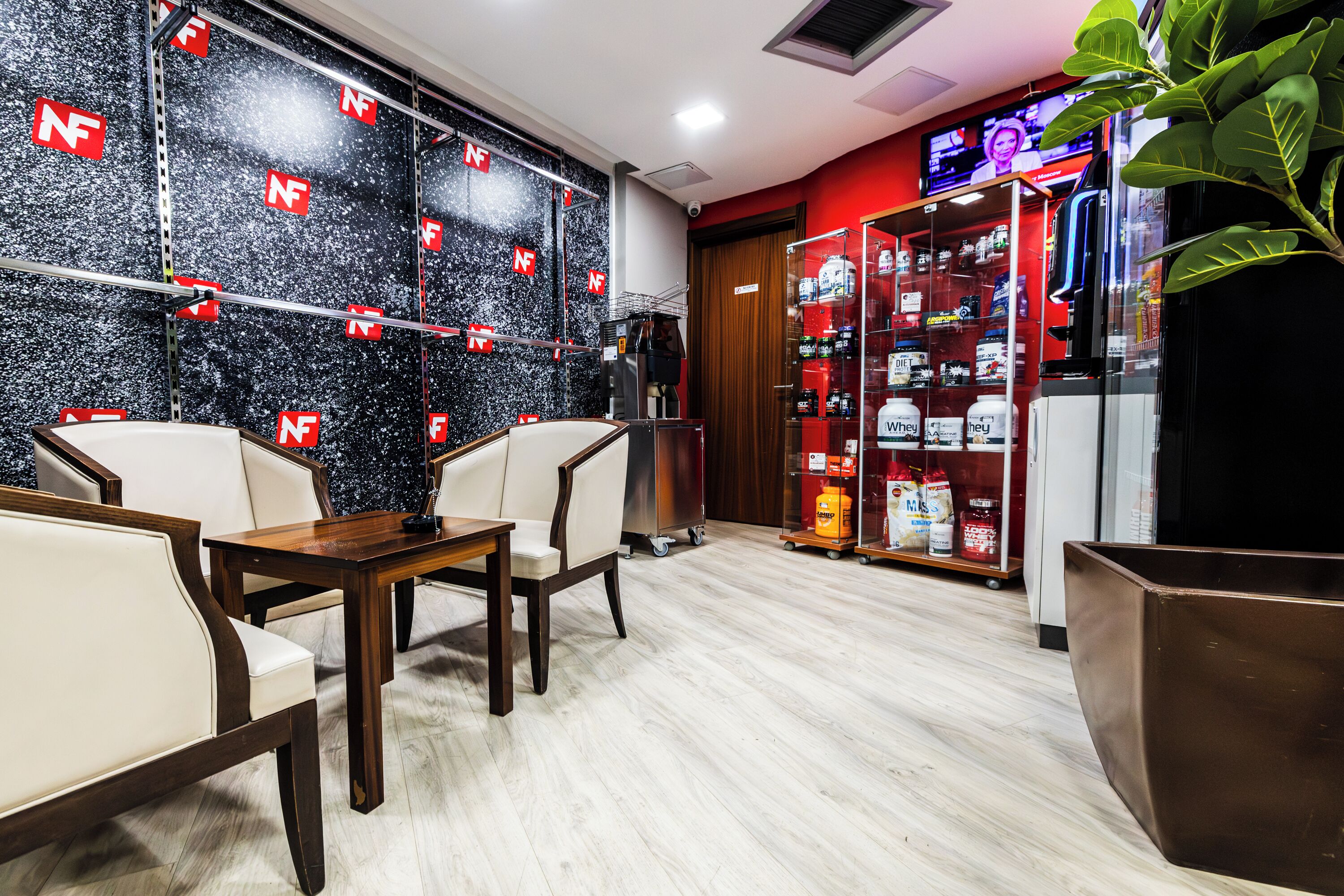 Un hall d’hôtel avec un mur en marbre noir, un comptoir d’accueil et un espace détente avec des fauteuils.