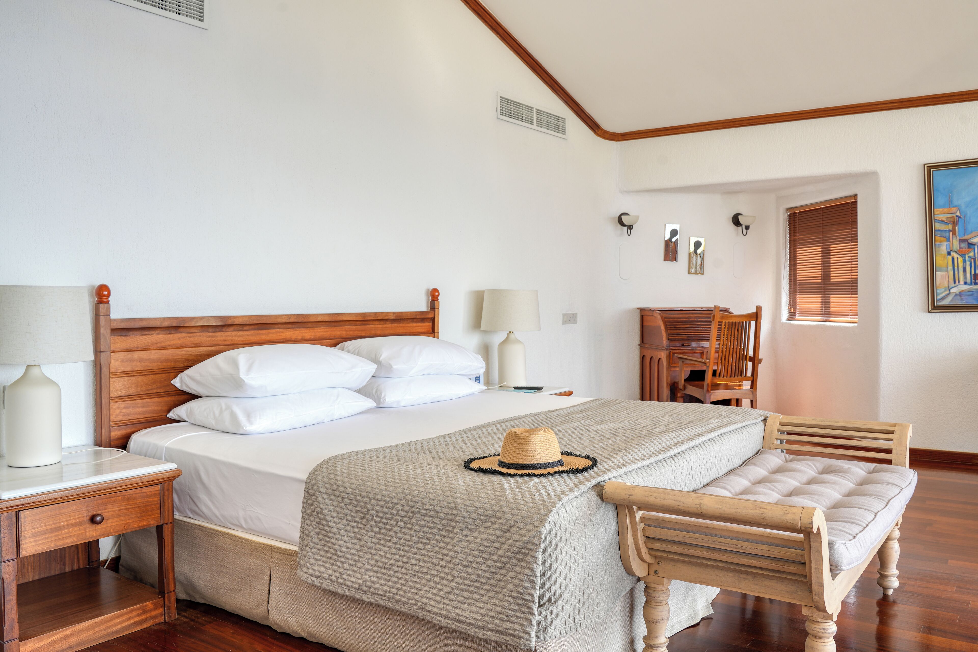 Un dormitorio ordenado con una cama de madera, mesitas de noche, una silla y un escritorio.