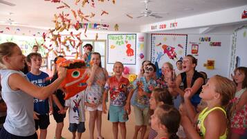 A group of children in a classroom with educational posters on the walls.