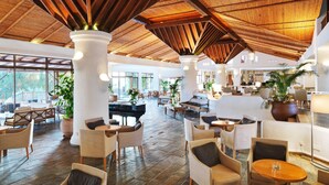 A spacious lobby with a high wooden ceiling, comfortable seating areas, and large windows offering natural light. - Coral Beach Hotel and Resort (Pegeia)