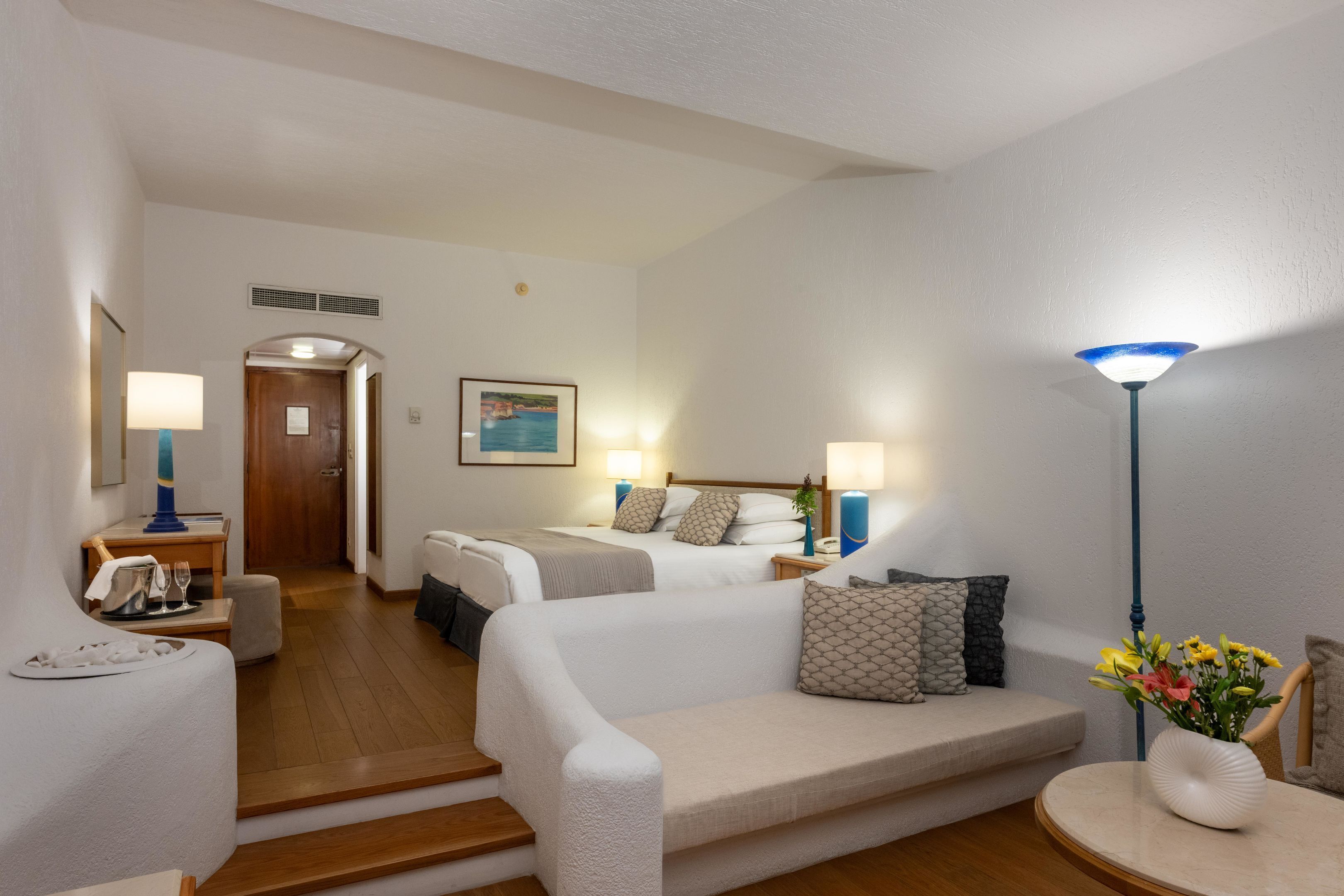 Ein Hotelzimmer mit Bett, Sofa, Esstisch und Lampe.