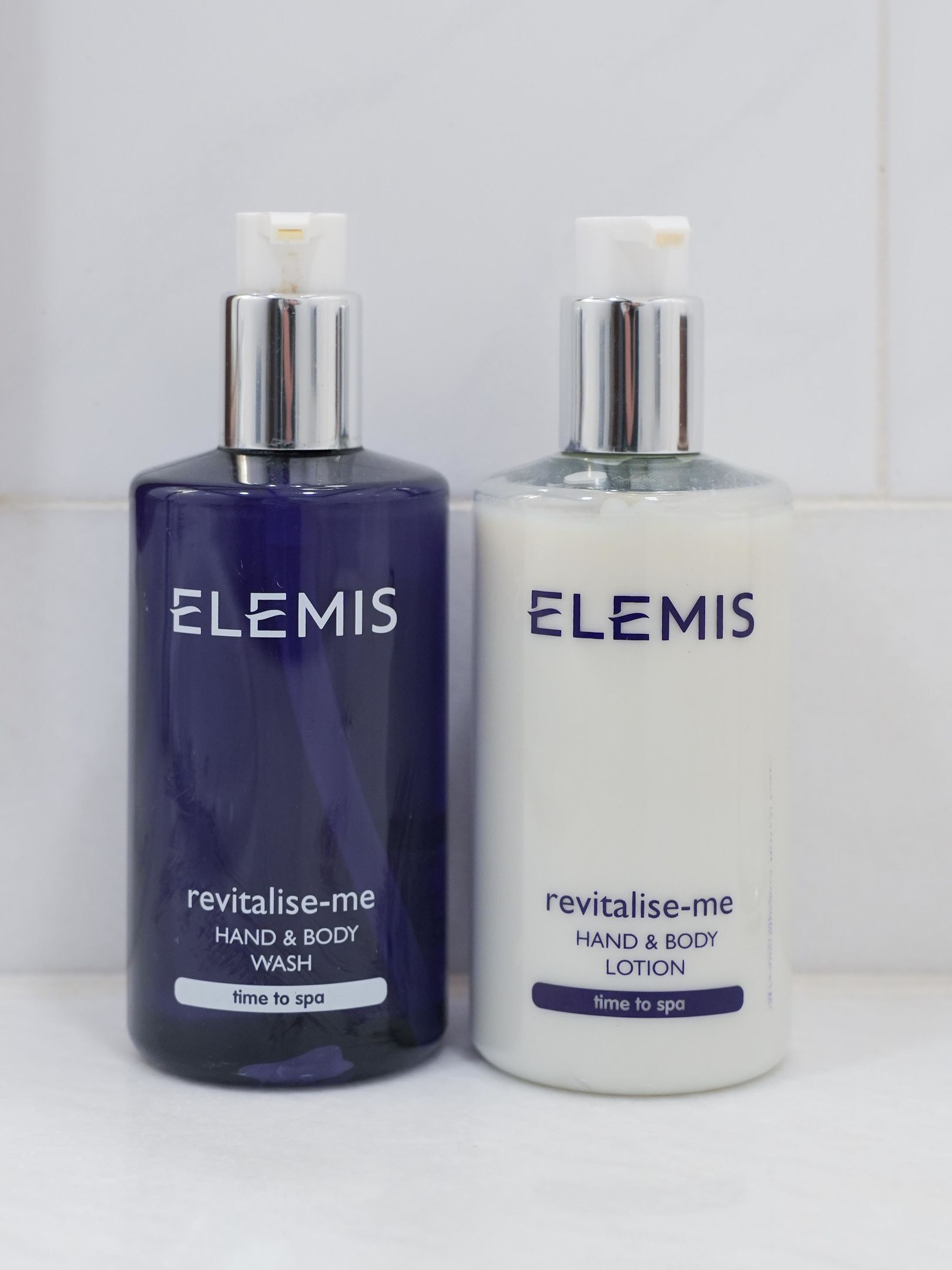 Two Elemis hand and body wash bottles, one in blue and one in white, labeled for hand and body wash and lotion.