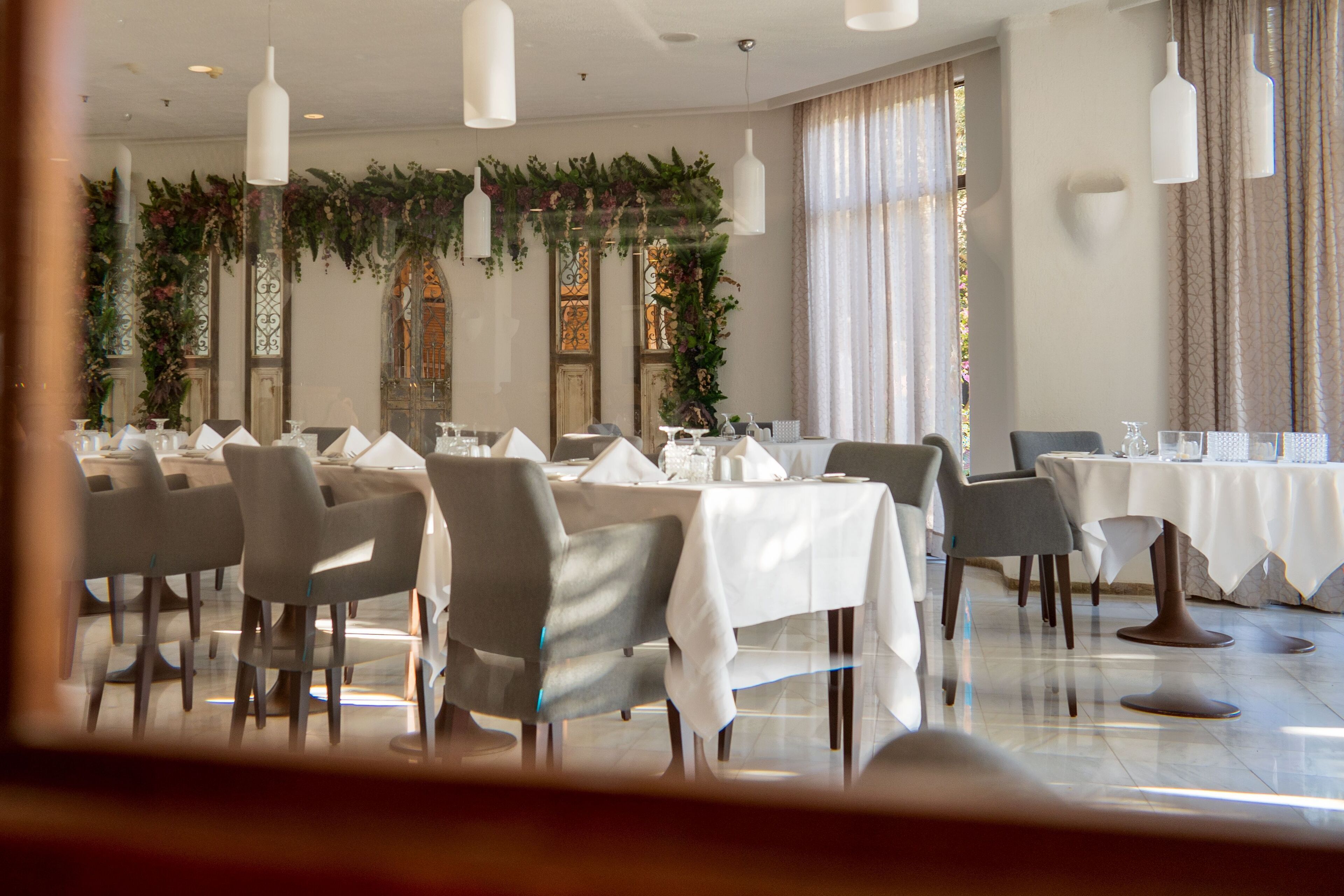 A dining area with tables set for service, chairs, and hanging pendant lights.