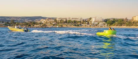 A coastal scene with a yellow boat and a green inflatable raft on the water.