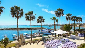 A beachfront resort with palm trees, a marina with boats, and outdoor seating areas. - Coral Beach Hotel and Resort (Pegeia)